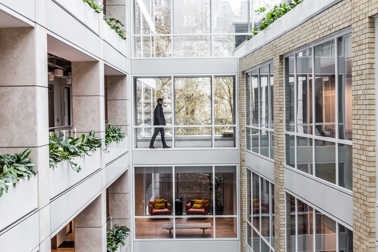 man walking down the hallway of a modern office building 