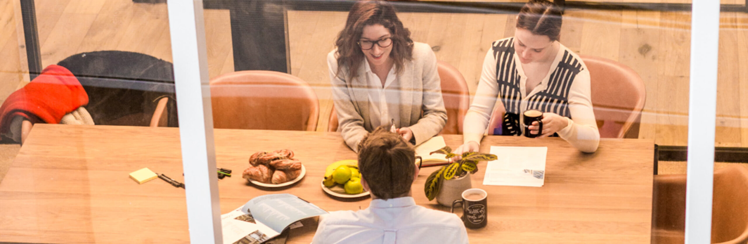 3 people working around a conference table in an office